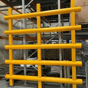 Yellow anti topple barrier protecting racking and loose stacked materials in a warehouse environment