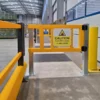 Close up of a pedestrian safety gate with yellow polymer barriers beside a warehouse walkway