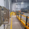 Elevated view of polymer barriers, pedestrian gates and a marked walkway inside a logistics warehouse
