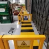 Yellow polymer pedestrian safety gate at a black and yellow crossing in front of a loading bay door