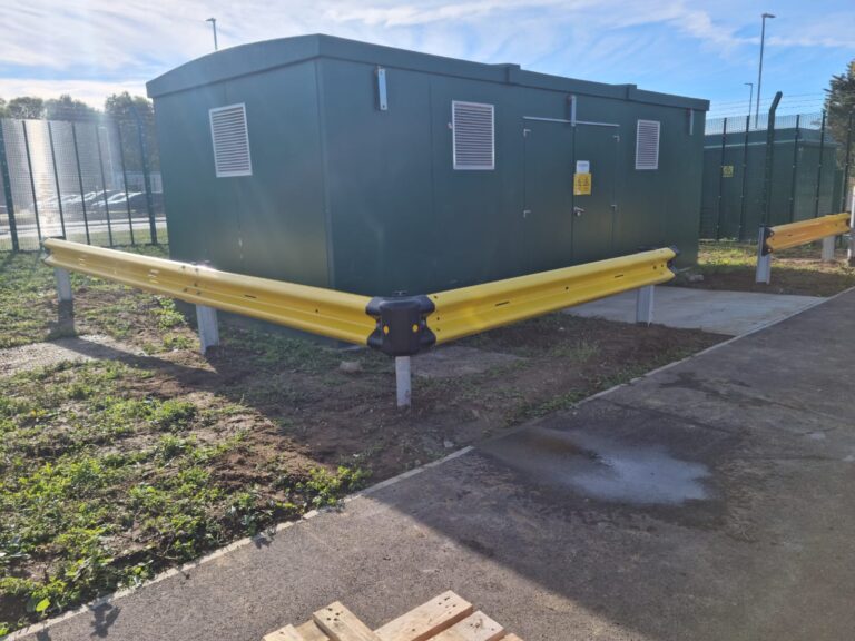 Yellow powder‑coated Armco protecting an electrical enclosure.