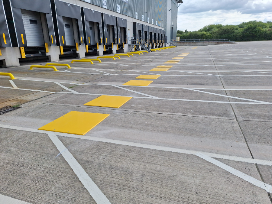 Yellow polymer landing plates and wheel guides installed at an HGV loading bay to assist safe vehicle alignment and docking operations.