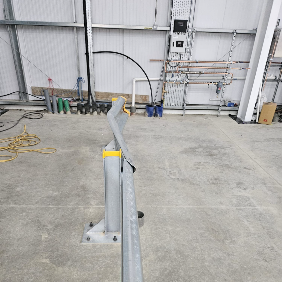 Bent Armco safety barrier beside a vehicle route in a warehouse