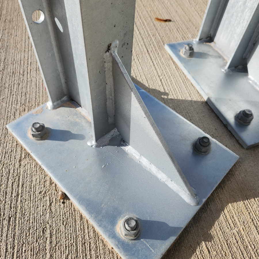 Close-up of four floor anchors securing an Armco barrier baseplate to concrete